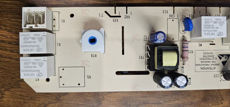 Płyta PCB z komponentami elektronicznymi, w tym przekaźnikami i kondensatorami.
