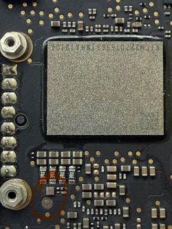 Zbliżenie PCB z dużą metalową osłoną i zaznaczonym na brązowo małym przypalonym elementem