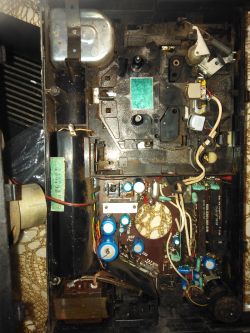 Wnętrze starego magnetofonu z widocznymi podzespołami elektronicznymi i przewodami.