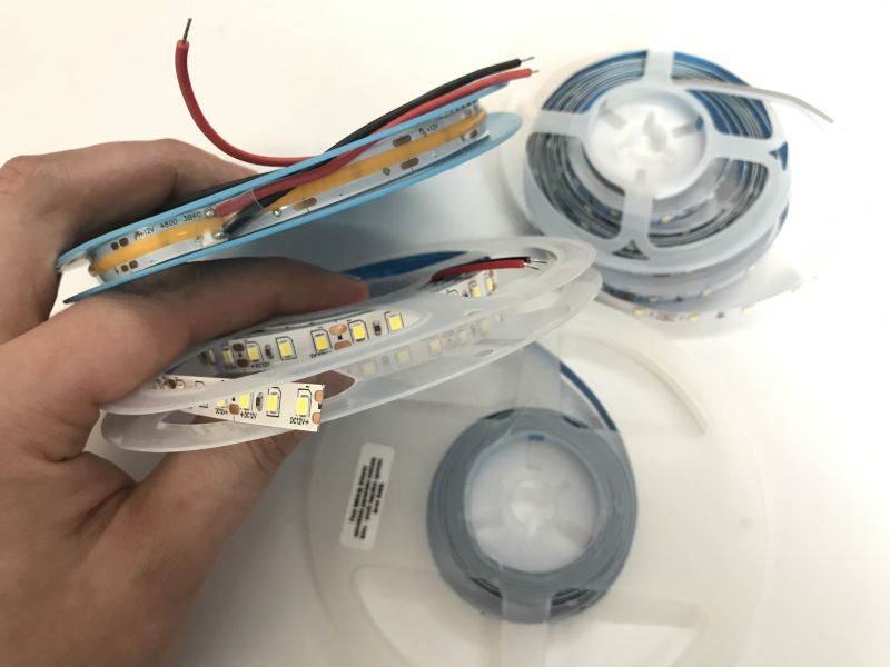 Various 12V LED strip reels held in a hand, showing different types and light shades.