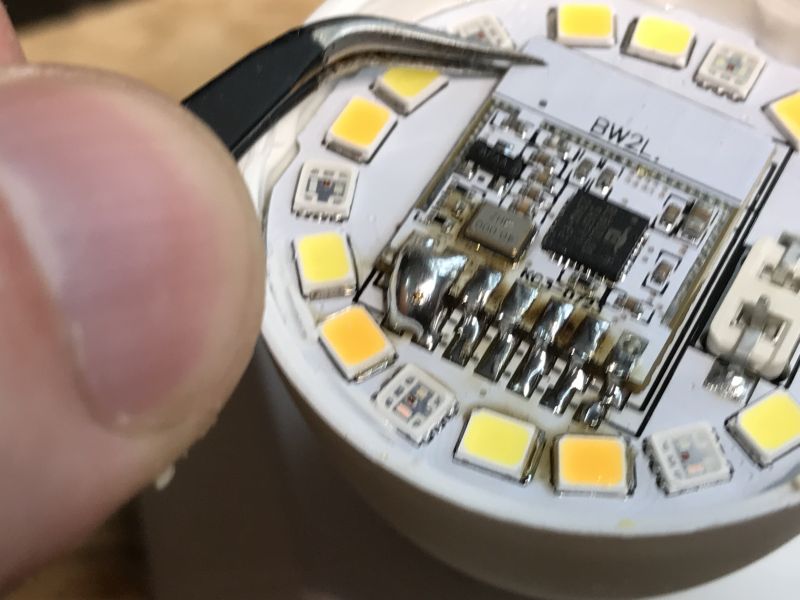 LED Board with Electronic Components Close-up of an LED board with LEDs and electronic components, and tweezers held nearby.