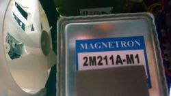 Zbliżenie na magnetron 2M211A-M1 i biały wentylator w kuchence mikrofalowej