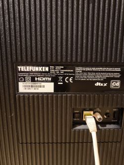 Back of a Telefunken TV with model label and ports; white cable plugged into the LAN port