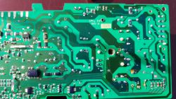 Zdjęcie zielonej płytki drukowanej z widocznym obwodem i komponentami elektronicznymi. W prawym dolnym rogu zaznaczono czerwonym zakreślaczem potencjalne miejsce zwarcia.