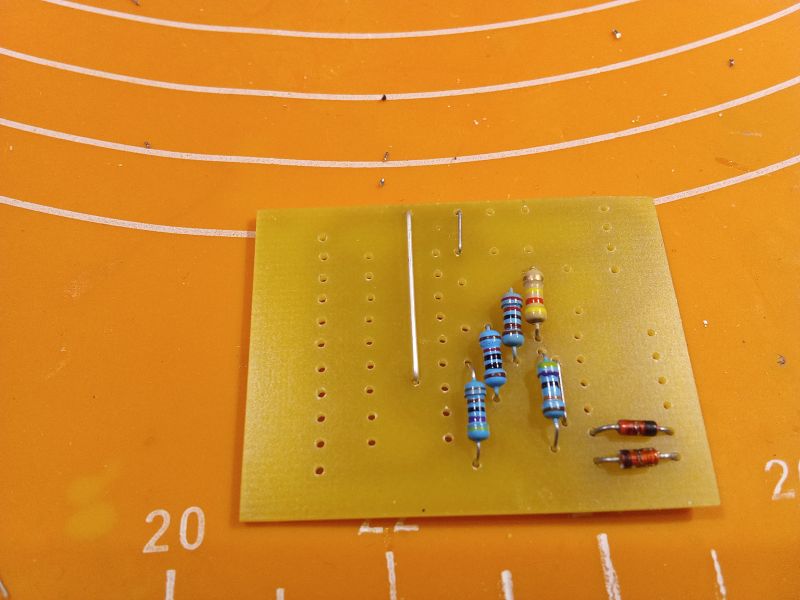 Prototype board with resistors and diodes on an orange background.