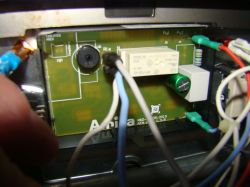 Zbliżenie na wnętrze panelu elektronicznego kuchenki z różnymi przewodami.