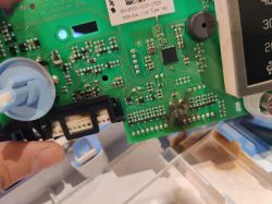 Zbliżenie na płytkę drukowaną z widocznymi elementami elektronicznymi i przypalonym miejscem.