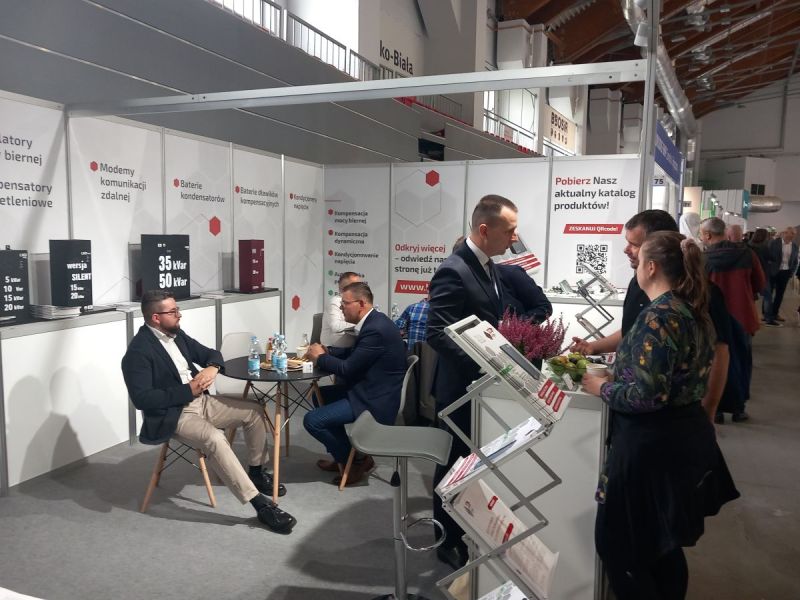 Stoisko targowe z materiałami informacyjnymi i rozmowami przedstawicieli firmy z odwiedzającymi
