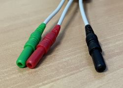 Trzy wtyki żeńskie w kolorach zielonym, czerwonym i czarnym na drewnianej powierzchni.