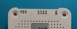 Close-up of a label with pin markings on a white electronic device casing.