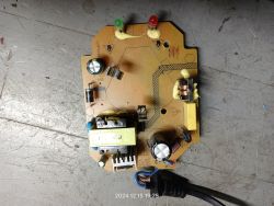 Płytka drukowana z różnymi komponentami elektronicznymi, w tym kondensatorami, diodami i cewkami, na szarej powierzchni.