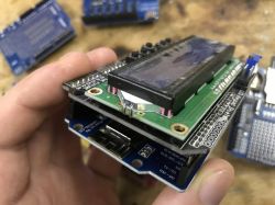A hand holding an electronic device with an LCD display module.