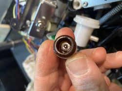 Osoba trzymająca mały plastikowy element z ekspresu do kawy.