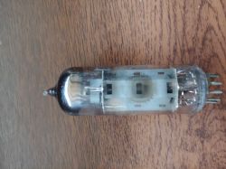 Lampa elektronowa 6P14P z ciemnym przebarwieniem na szczycie bańki na tle drewnianego stołu.