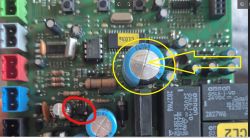 Płytka PCB z elementami; żółte kółko i strzałka wskazują duży niebieski kondensator