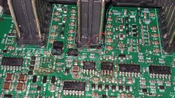 Zbliżenie na płytkę drukowaną z kilkoma komponentami elektronicznymi i oznaczeniami pinów, w tym przypalone miejsce.