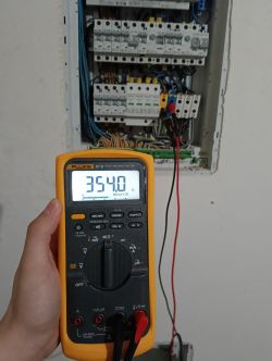 Pomiar napięcia w rozdzielnicy za pomocą multimetru Fluke z wyświetlonym wynikiem 354,0.