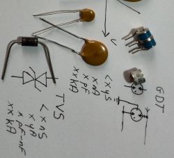 Kondensatory, warystory i inne elementy elektroniczne na kartce z symbolami