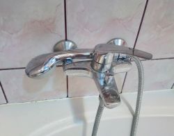 Chromowana bateria prysznicowa GROHE z wężem i słuchawką w pozycji montażu naściennego