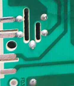 Zbliżenie zielonej płytki PCB z przelotkami, ścieżkami i punktami lutowniczymi