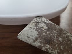 Close-up of a rusty blade touching a white plastic object