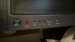 Panel przedni obudowy komputera z przyciskami i portami USB, przycisk oznaczony na czerwono