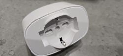 Close-up of a white grounded electrical outlet lying on a gray surface