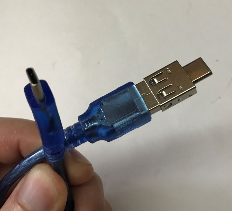 Close-up of a blue USB cable with a USB-A plug and a small USB-C plug held in a hand.