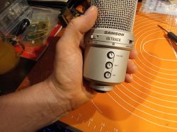 Mikrofon pojemnościowy SAMSON G Track trzymany w dłoni z widocznymi przyciskami regulacji.