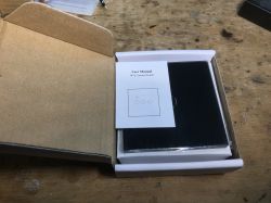 WiFi SmartLED Light Switch Set in Packaging An open box with a user manual and a glass WiFi Smart Switch panel inside.