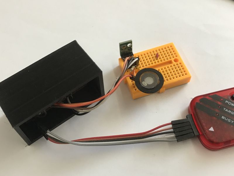 Close-up photo of a prototype board with a PIC18F2550 microcontroller, 7-segment display, connected wires, resistors, and a photoresistor.