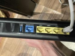 Panel tylni routera z portami LAN, WAN i USB, jeden port LAN zajęty kablem ethernet.