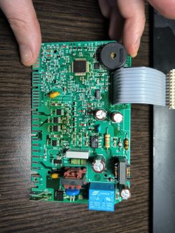 Płytka drukowana z elementami elektronicznymi trzymana przez ręce.