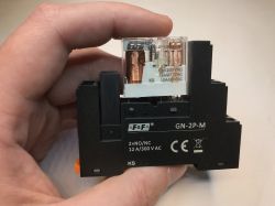 Przekaźnik elektromagnetyczny F&amp;F GN-2P-M trzymany w dłoni