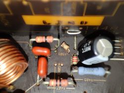 Zbliżenie na płytkę drukowaną z różnymi elementami elektronicznymi, w tym rezystorami i kondensatorem.