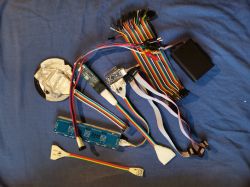 Zestaw programatora USBASP z kablami i adapterami na niebieskim tle.