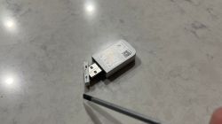 USB Adapter and Screwdriver on Light Countertop A USB adapter with an open cover on a light countertop, next to a thin screwdriver.