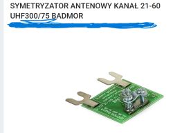 Mała zielona płytka drukowana – symetryzator antenowy UHF 300/75 BADMOR z dwoma metalowymi zaciskami i śrubami.