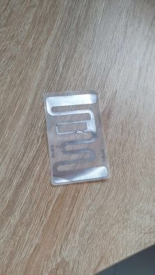 Przezroczysta plastikowa część z metalowymi elementami na drewnianym blacie.