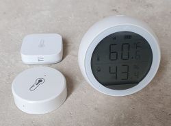 Three different ZigBee temperature sensors on a grey surface.