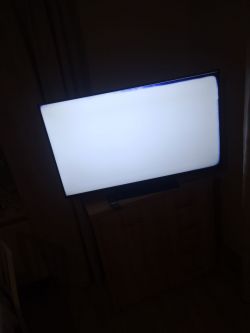 Ekran telewizora Hitachi z białym tłem i niebieskimi przebarwieniami na krawędziach.