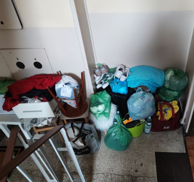 Stos worków i przedmiotów na klatce schodowej.