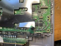 Widok wnętrza konsoli PlayStation SCPH-7502 z odkrytą płytą główną i dodatkowym elementem.