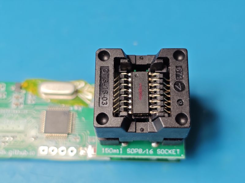 Close-up of a black SOP8/16 test socket on a PCB against a blue background