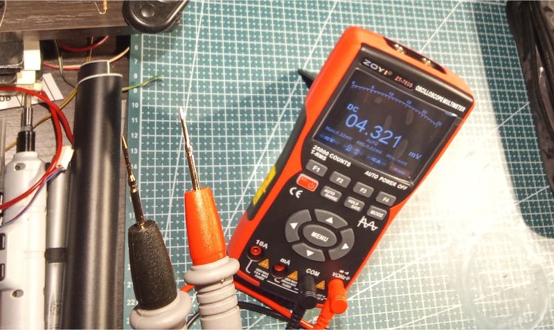 Cyfrowy miernik Zoyi ZT-703S z sondami pomiarowymi na macie technicznej