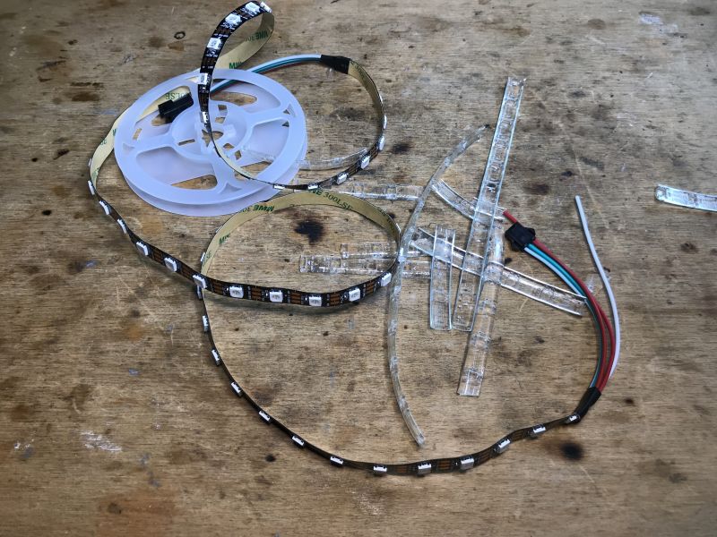WS2812B LED Strips with Accessories on Table WS2812B LED strips on a workshop table with wires and plastic covers.