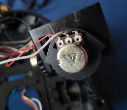 Potencjometr B 100K-55 w joysticku Zbliżenie na potencjometr B 100K-55 z trzema zaciskami, zamontowany w joysticku, z podłączonymi przewodami.