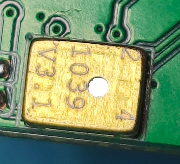 Close-up of a gold electronic component labeled V3.1 1039 on green PCB