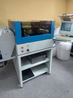 Automat montażowy M60 z niebiesko-szarą obudową, oknem z przezroczystego tworzywa oraz pulpitem sterującym z monitorem i klawiaturą.