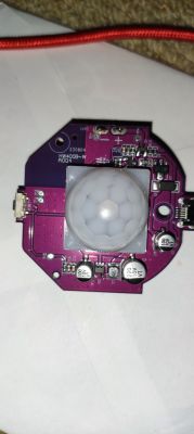 Electronic board with a PIR sensor on a purple background.